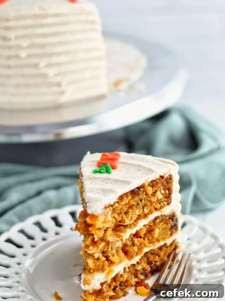 big thick slice of gf carrot cake on white plate with green tea towel and whole cake in the background.