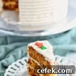 slice of gluten free carrot cake on white plate with whole cake on cake stand in the background.