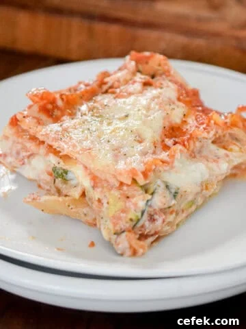 A slice of the vegetable lasagna is on white plates with a cutting board behind it.