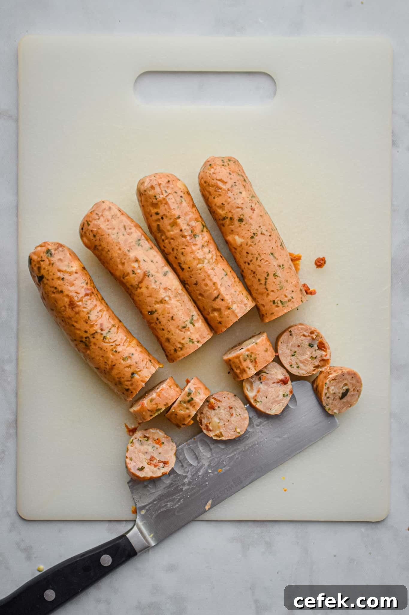 The chicken sausage is being cut on a wooden cutting board