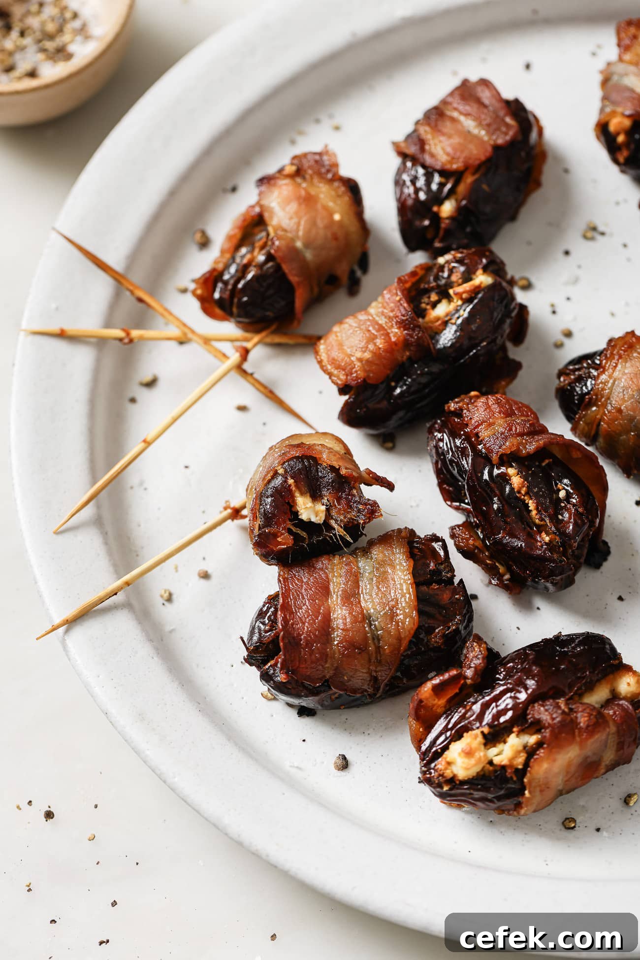 Close up of bacon-wrapped dates on a white plate. 