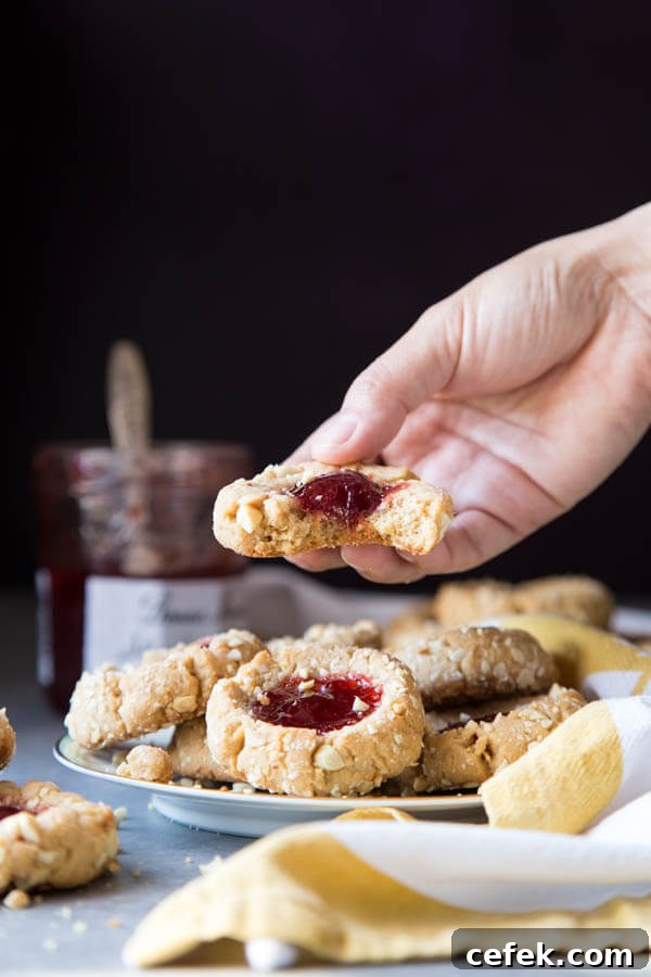 Picking up a jam thumbprint cookie from a plate