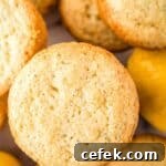 Overhead shot of lemon muffins stacked on a white surface with whole lemons in the background.
