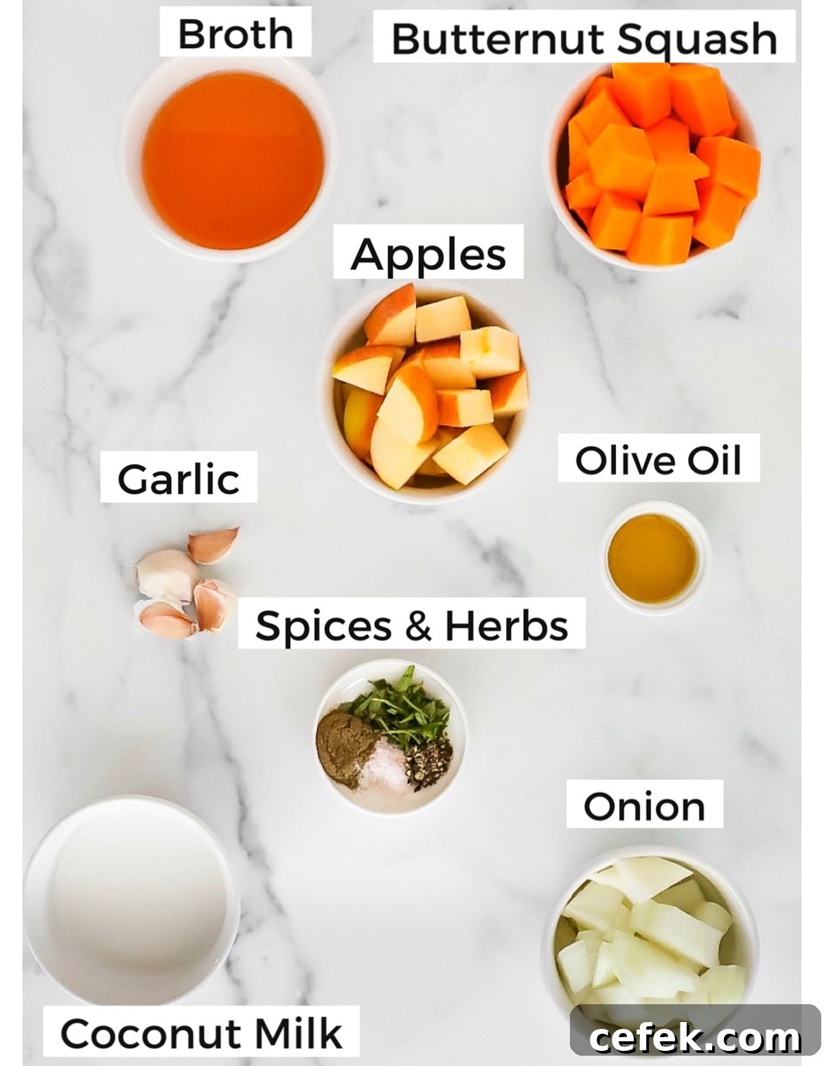 Labeled ingredients in small white bowls including: broth, butternut squash, apples, olive oil, garlic, spices and herbs, onion, and coconut milk
