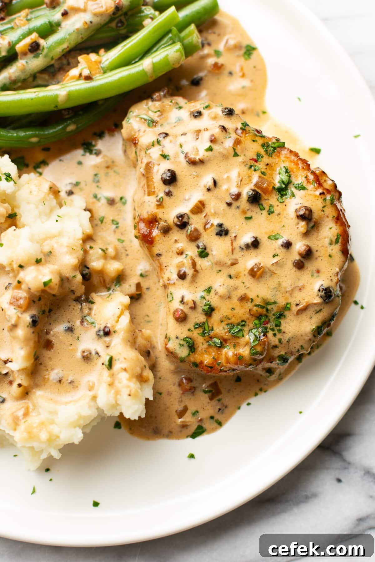 a plate with peppercorn pork chops, green beans, and mashed potatoes