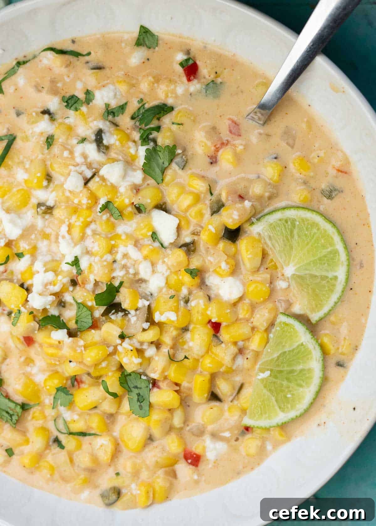 a white bowl filled with Mexican Street Corn Soup, garnished with lime wedges