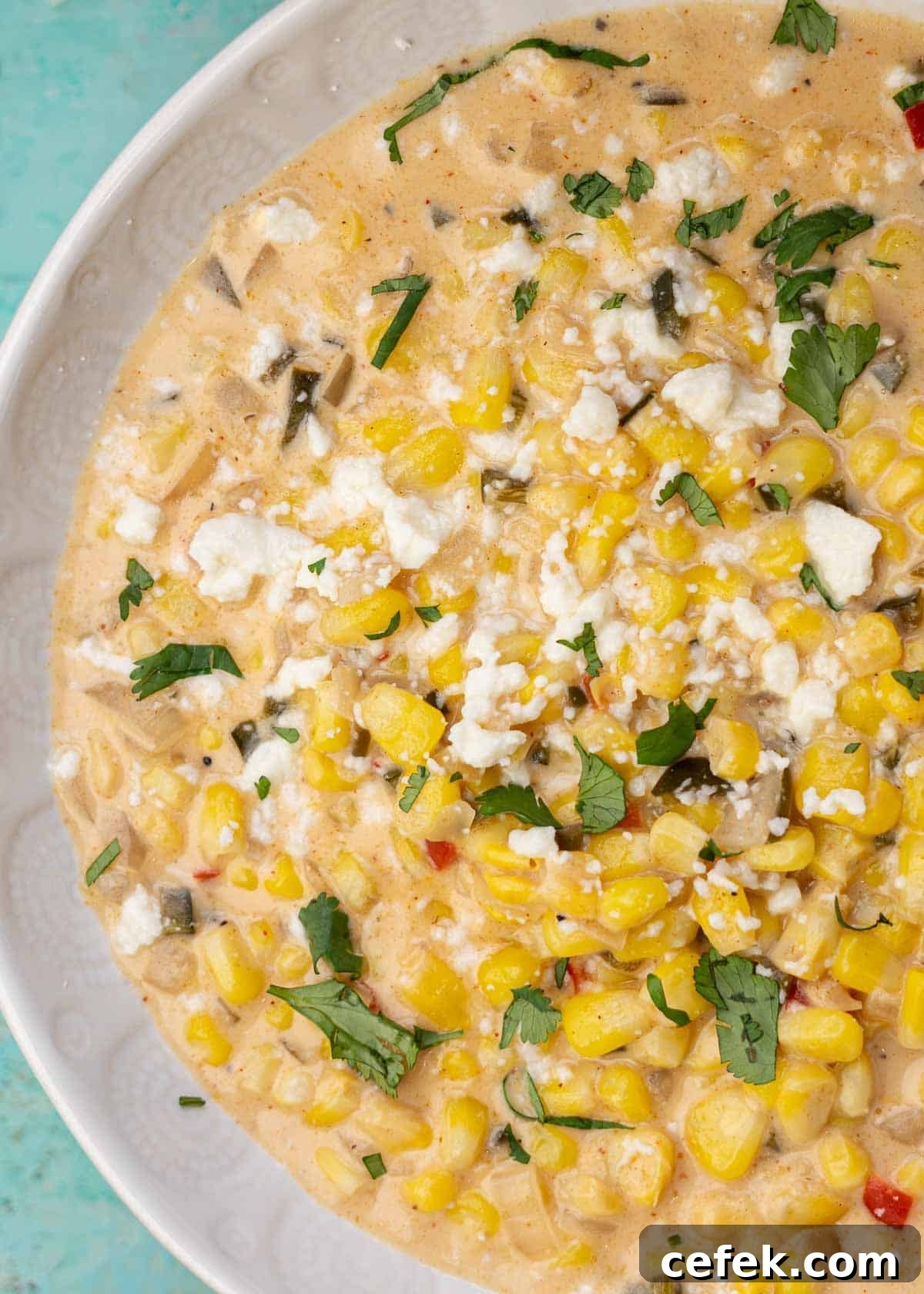 a white bowl filled with creamy, spicy corn soup topped with cilantro and cotija