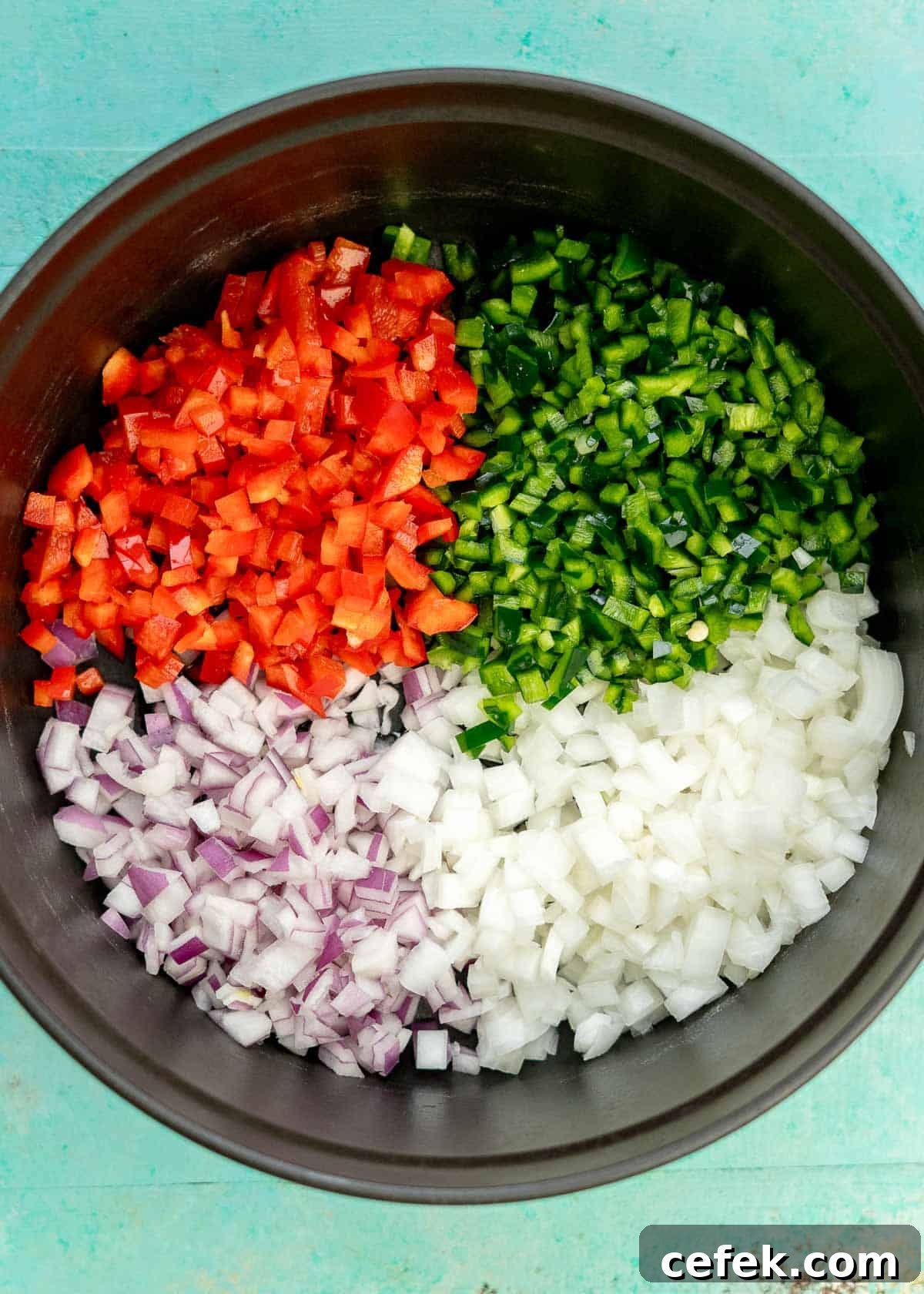 diced red bell pepper, poblano pepper, jalapeno pepper, red onion, and white onion in a cast iron dutch oven