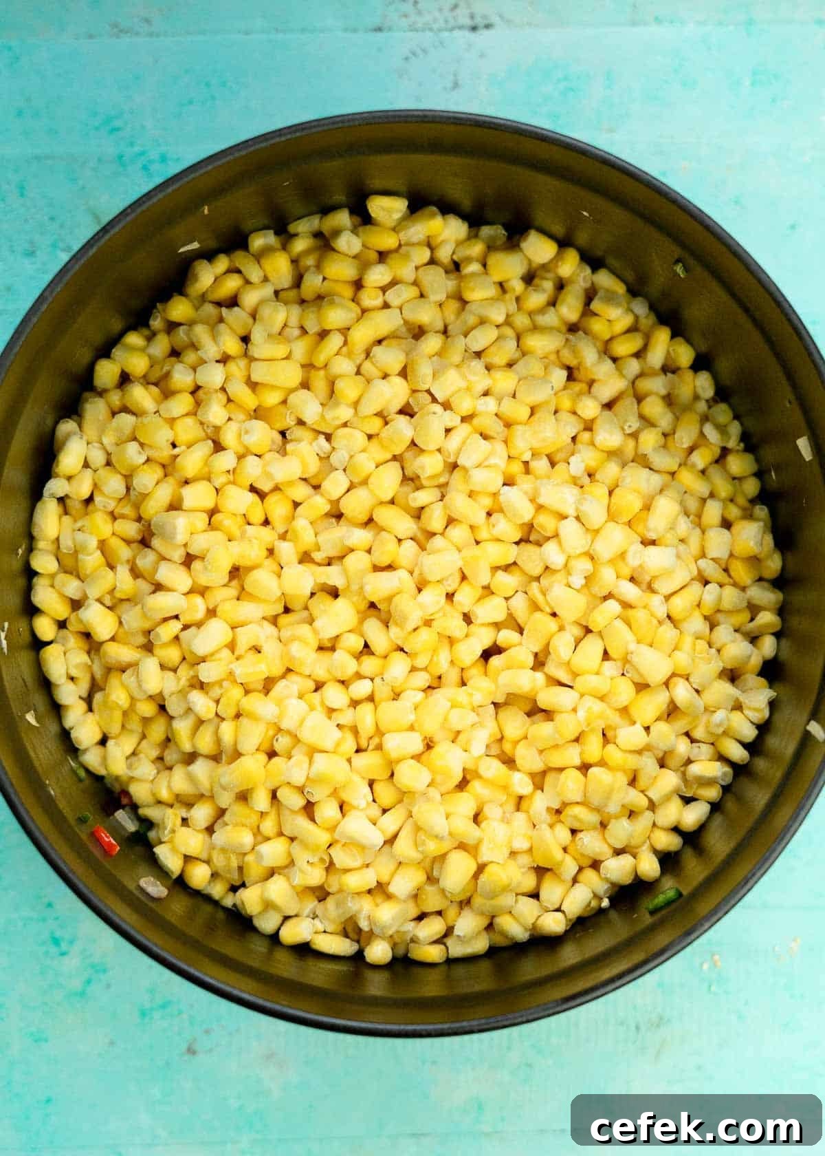 frozen corn added to a soup pot full of sauteed onions and peppers