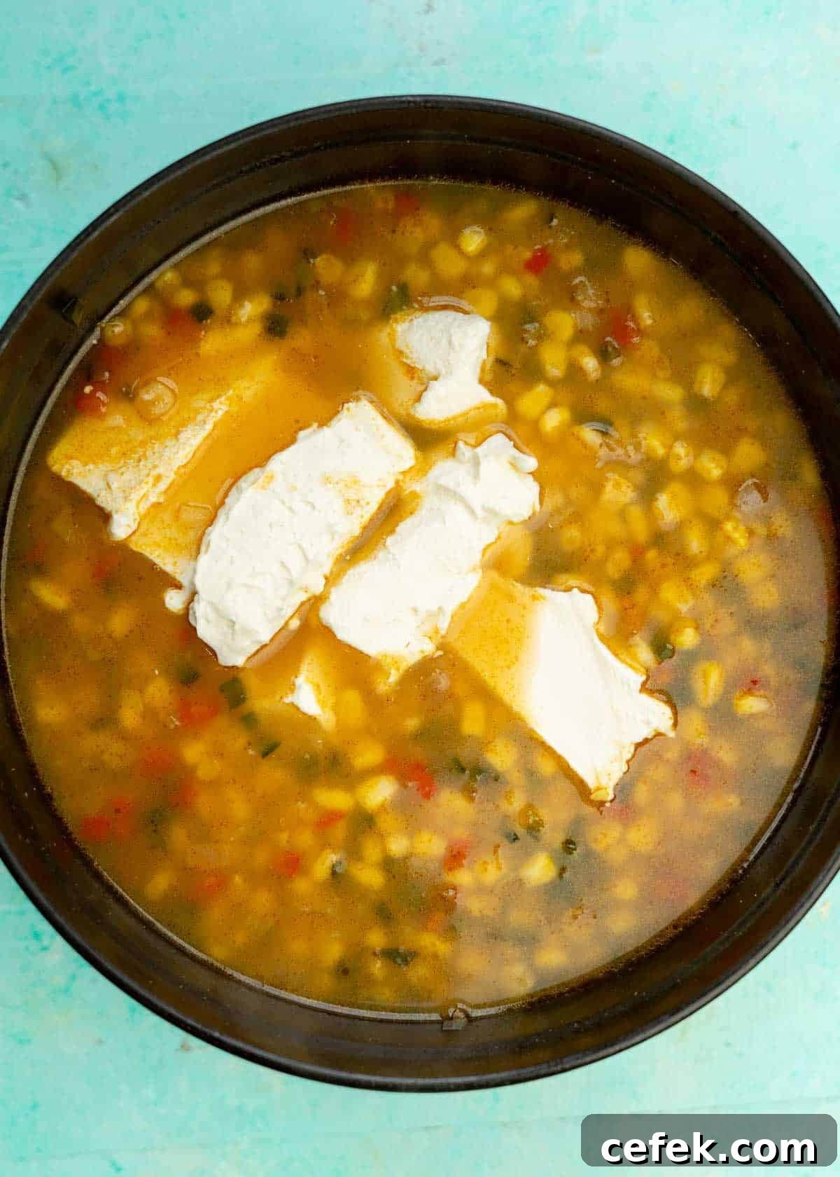 cream cheese added to mexican street corn soup in a dutch oven