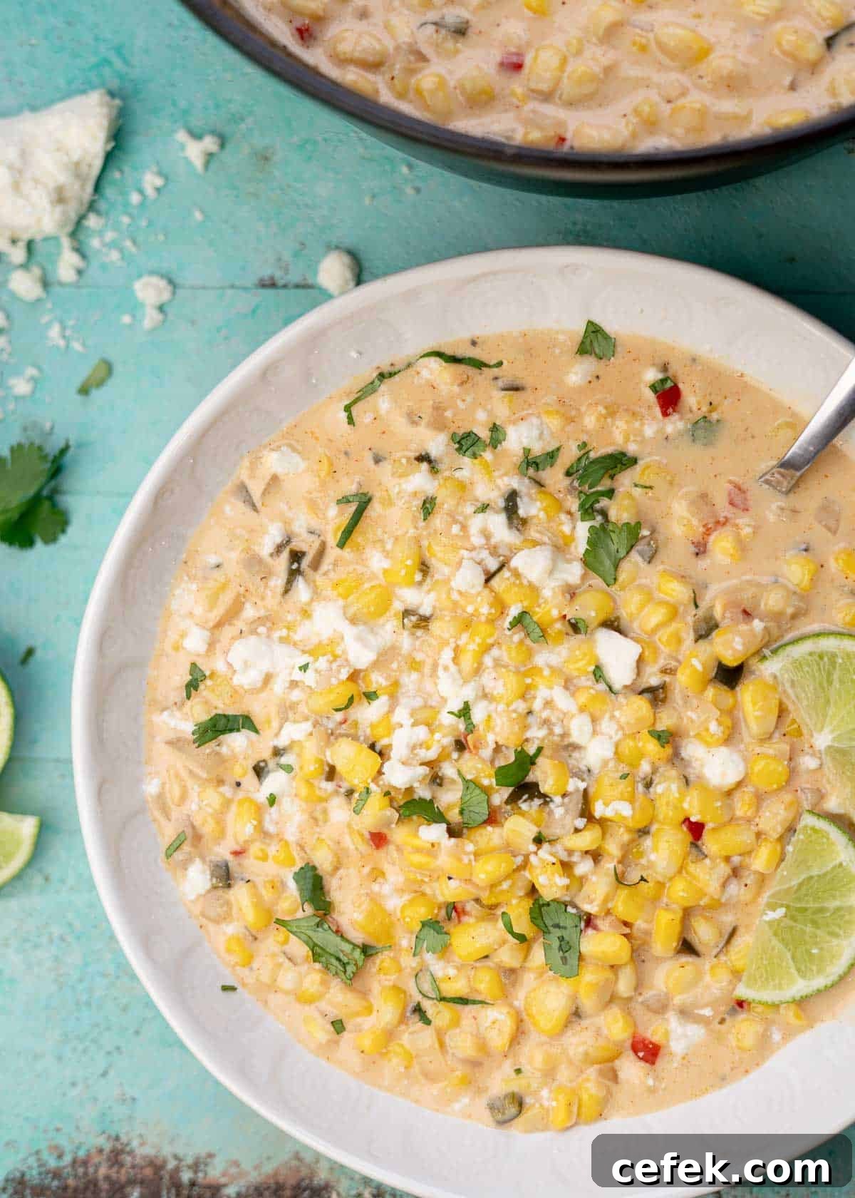 overhead shot showing a bowl of creamy Mexican Street Corn Soup garnished with cilantro, cotija cheese, and lime wedges