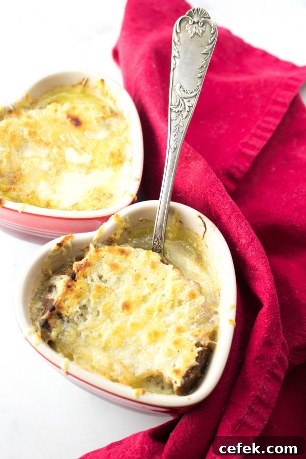 vegetarian French Onion Soup in French onion soup bowls topped with cheese with a silver spoon and red tea towel