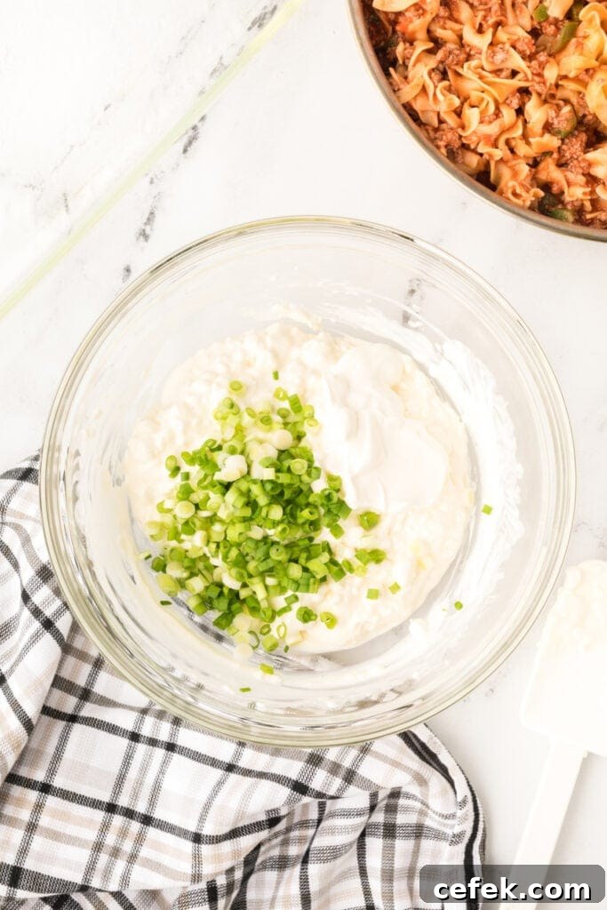 cottage cheese mixture with sour cream and chopped green onions in a glass bowl before mixing