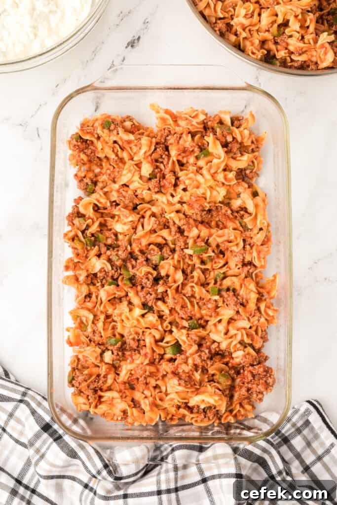 beef and noodle mixture spread into a glass baking dish