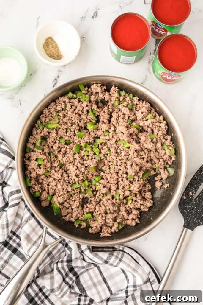 browned ground beef and green pepper mixture cooking in a skillet