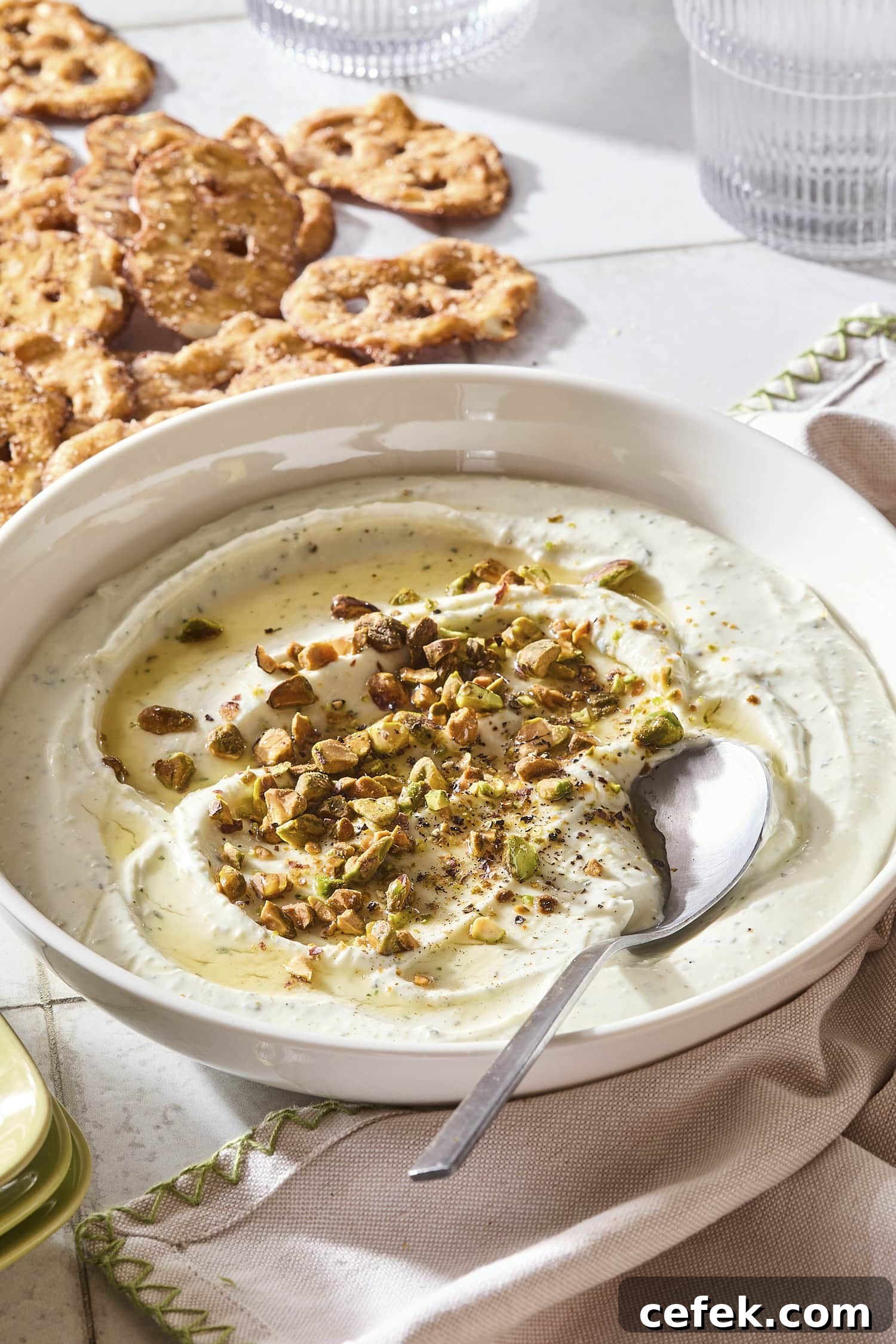 Whipped goat cheese dip topped with pistachios and hot honey with pretzels to the side.
