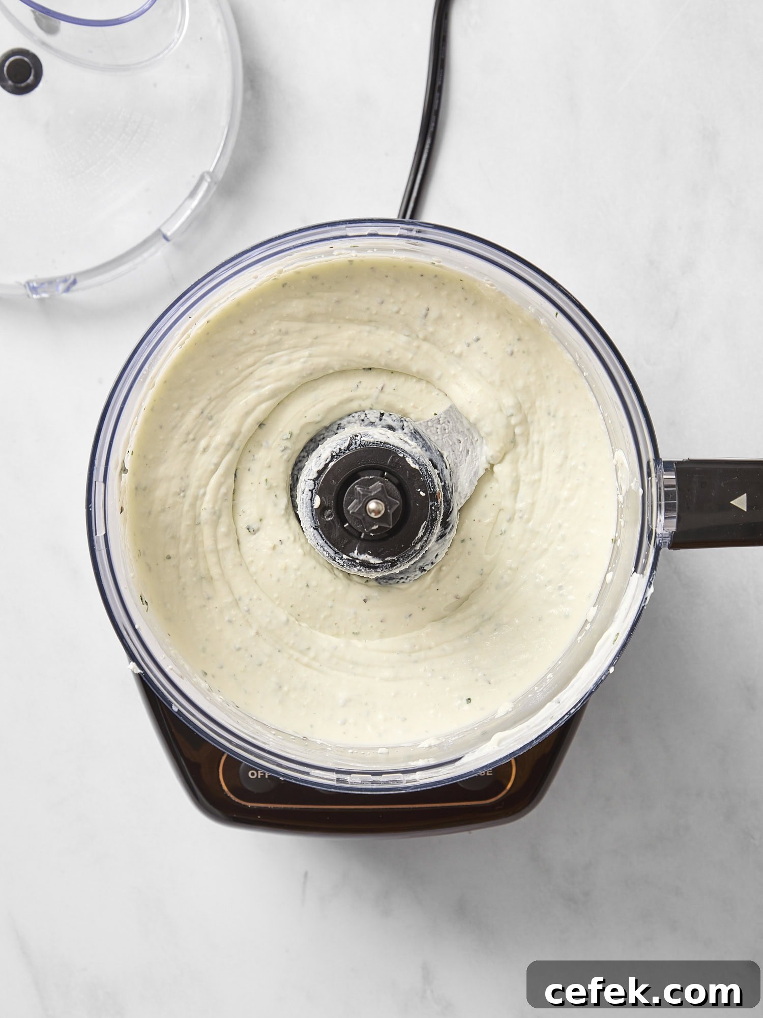Food processor with whipped goat cheese after being processed.