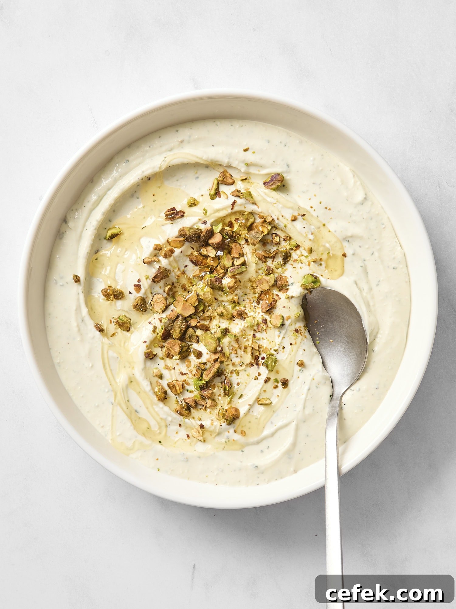 White bowl with whipped goat cheese dip with a spoon scooping out a serving.