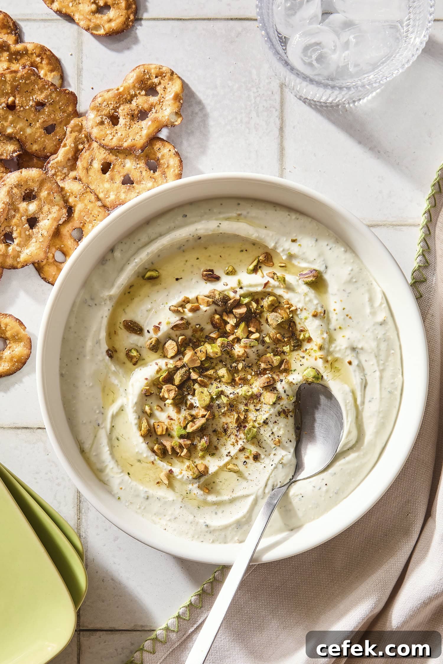 Bowl with goat cheese dip with pretzels to the side and topped with pistachios and hot honey.