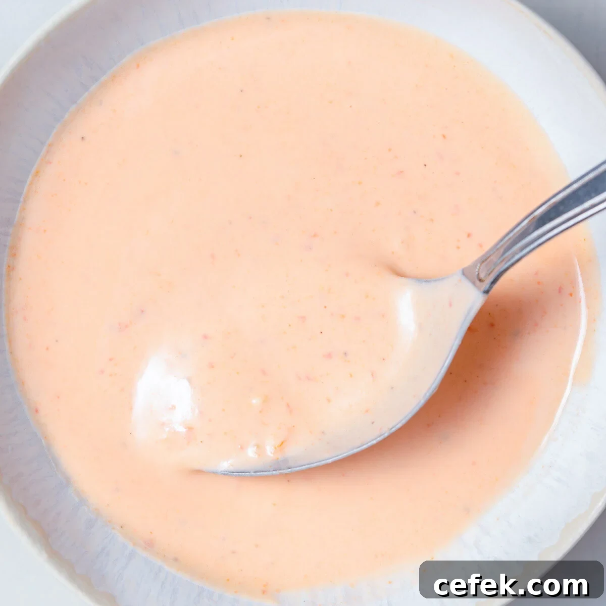a bowl full of Bang Bang sauce with a spoon in it.