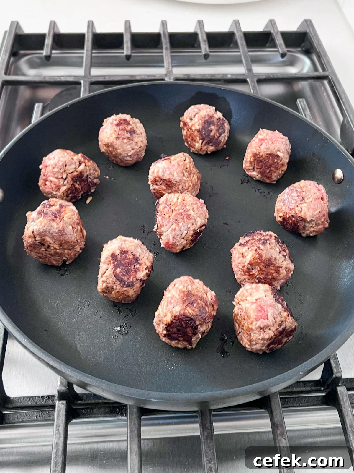 Meatballs browning in a pan.