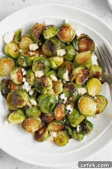 Roasted Brussels sprouts with goat cheese on a round plate with a vintage fork.