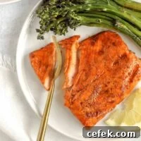 A gold fork cutting into a salmon fillet.