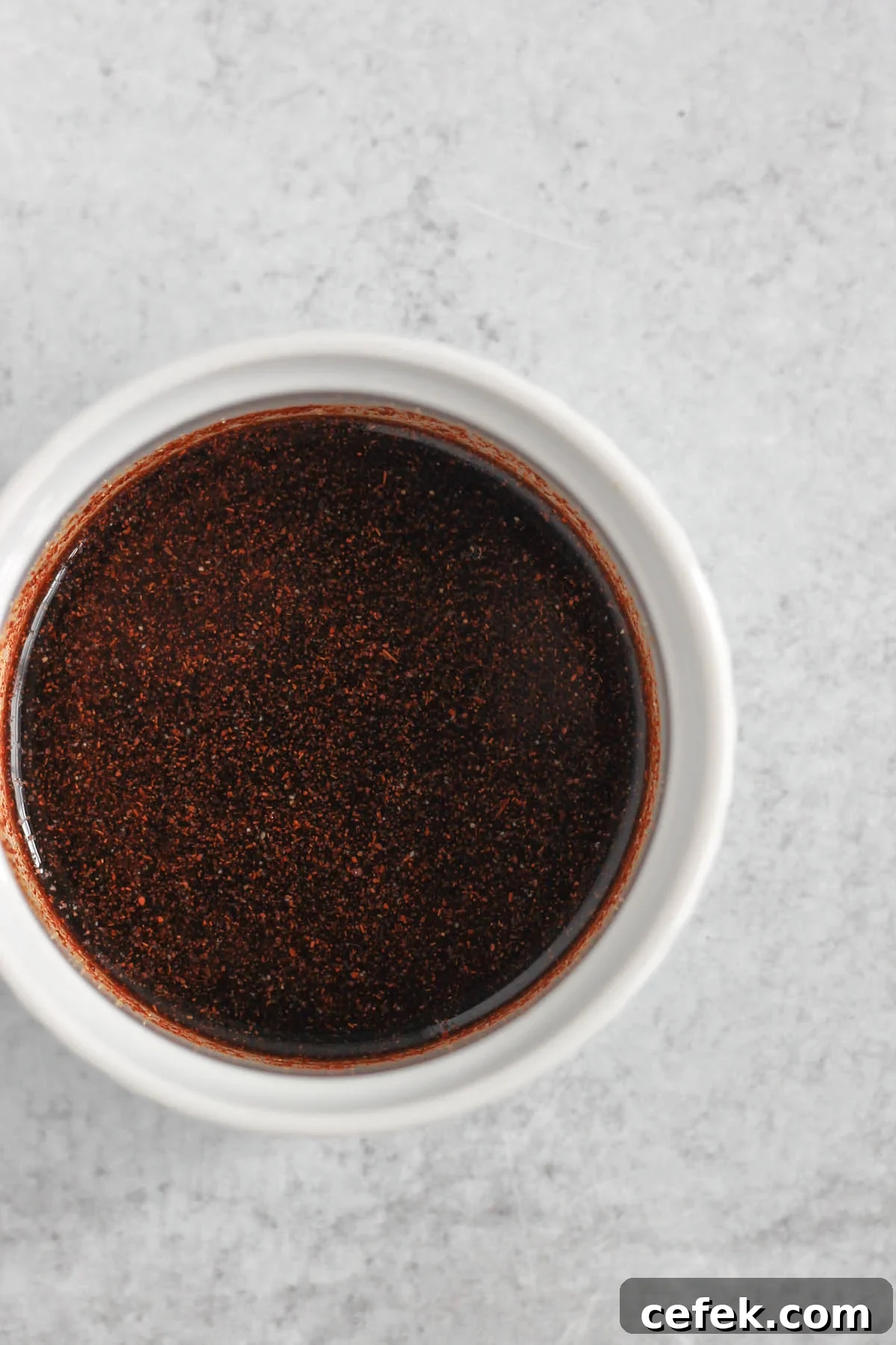 Dark red sauce in a small ramekin.