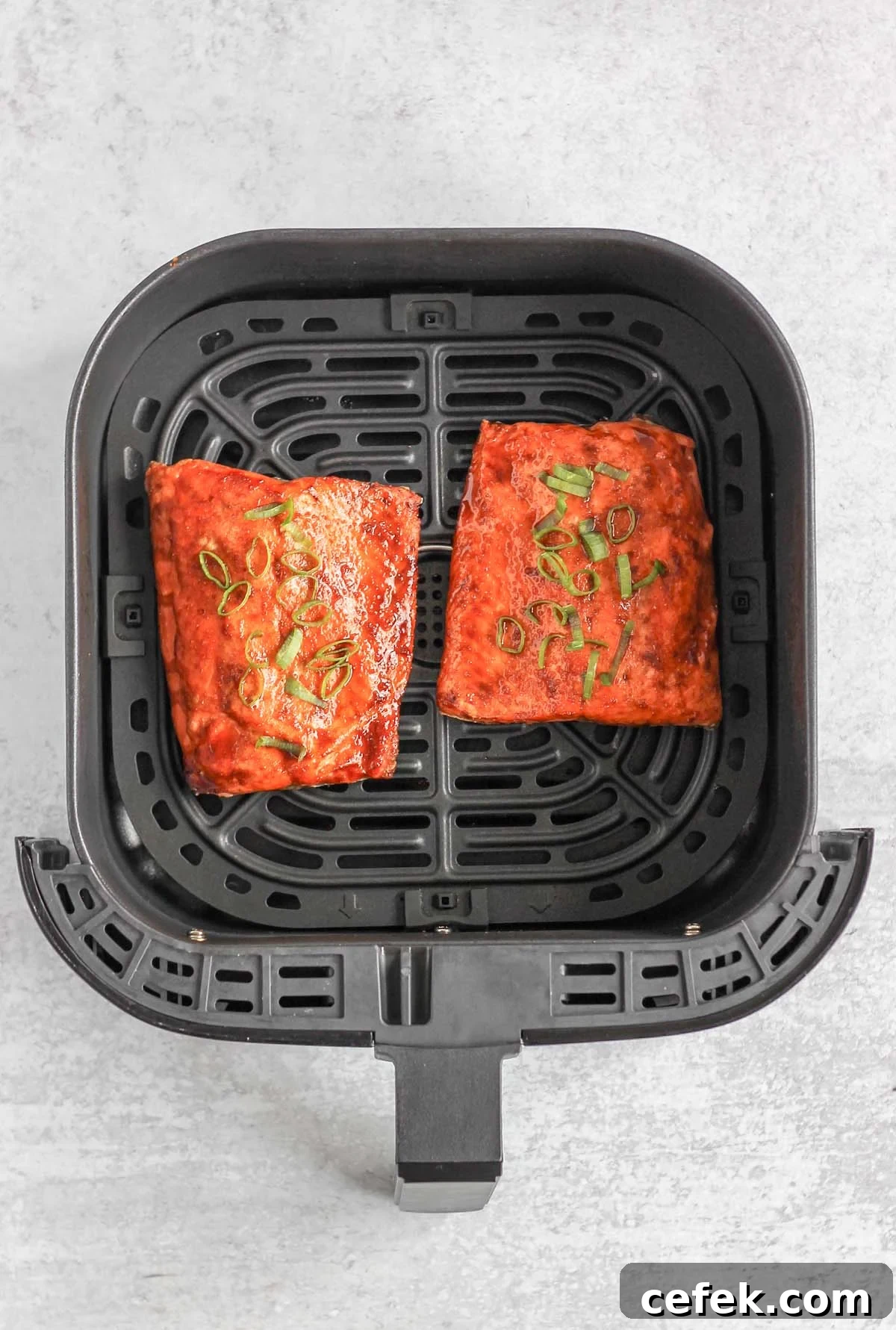 Cooked salmon fillets in an air fryer basket.