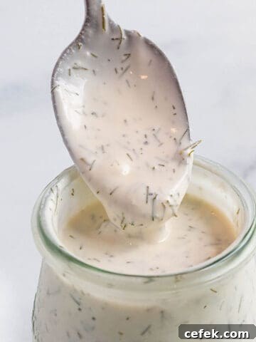 A small weck jar with a creamy sauce with a spoon scooping some out.