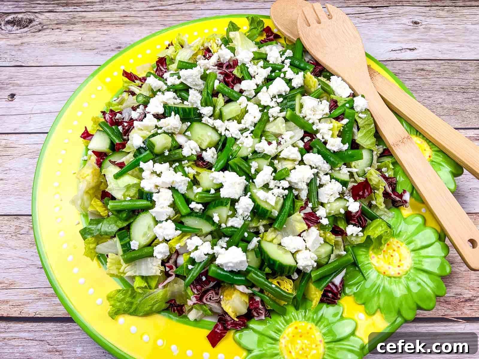 Mediterranean Chopped Salad with crumbled feta cheese, on a yellow plate with flower designs.