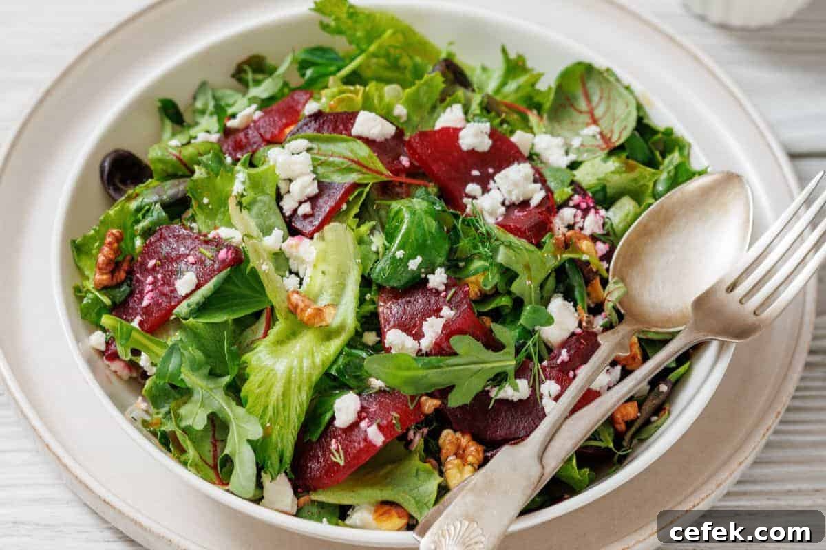 A plate of Beet Salad with Goat Cheese & Walnuts, served with a fork and spoon on the side.