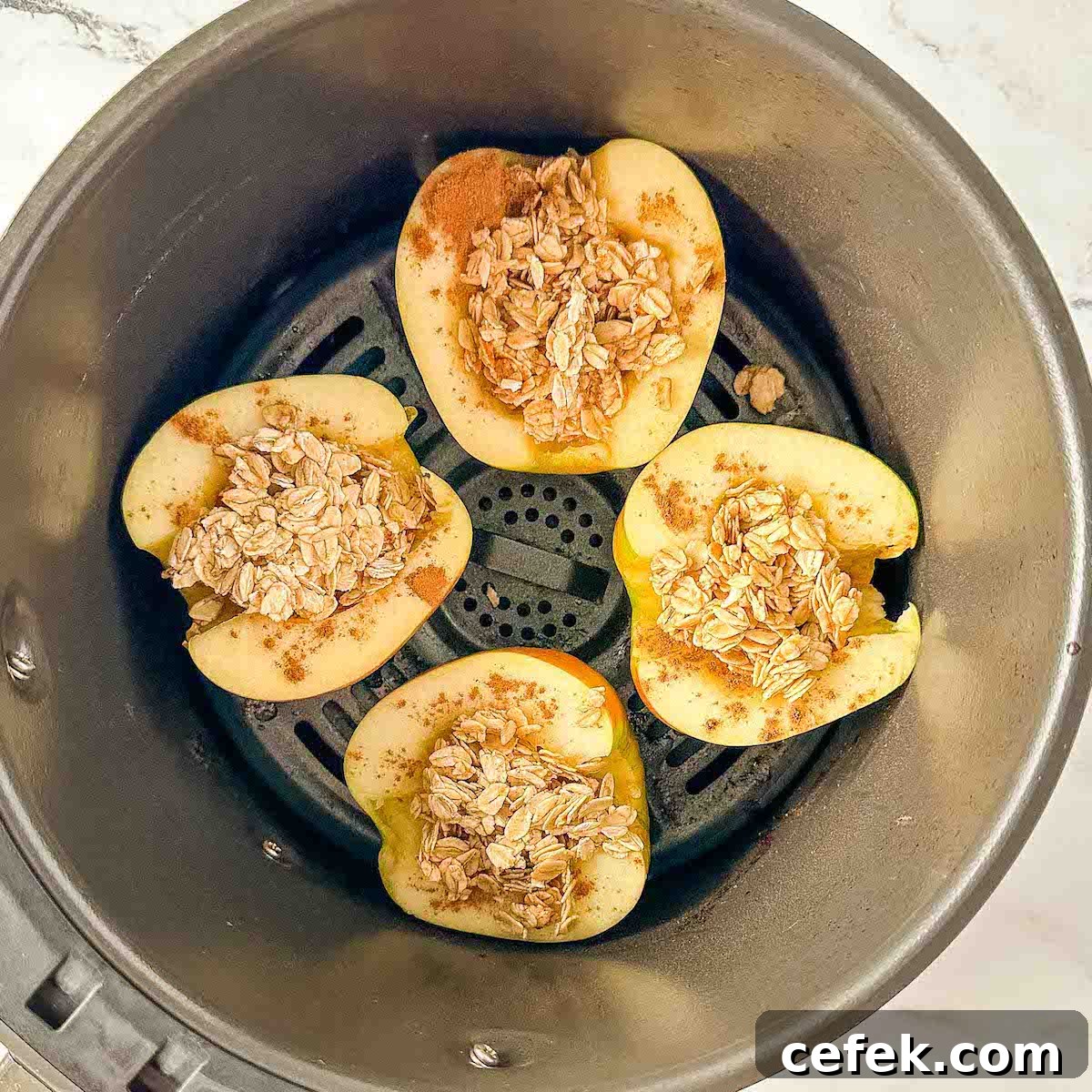 Apples filled with oat, cinnamon, maple mixture in an air fryer basket.