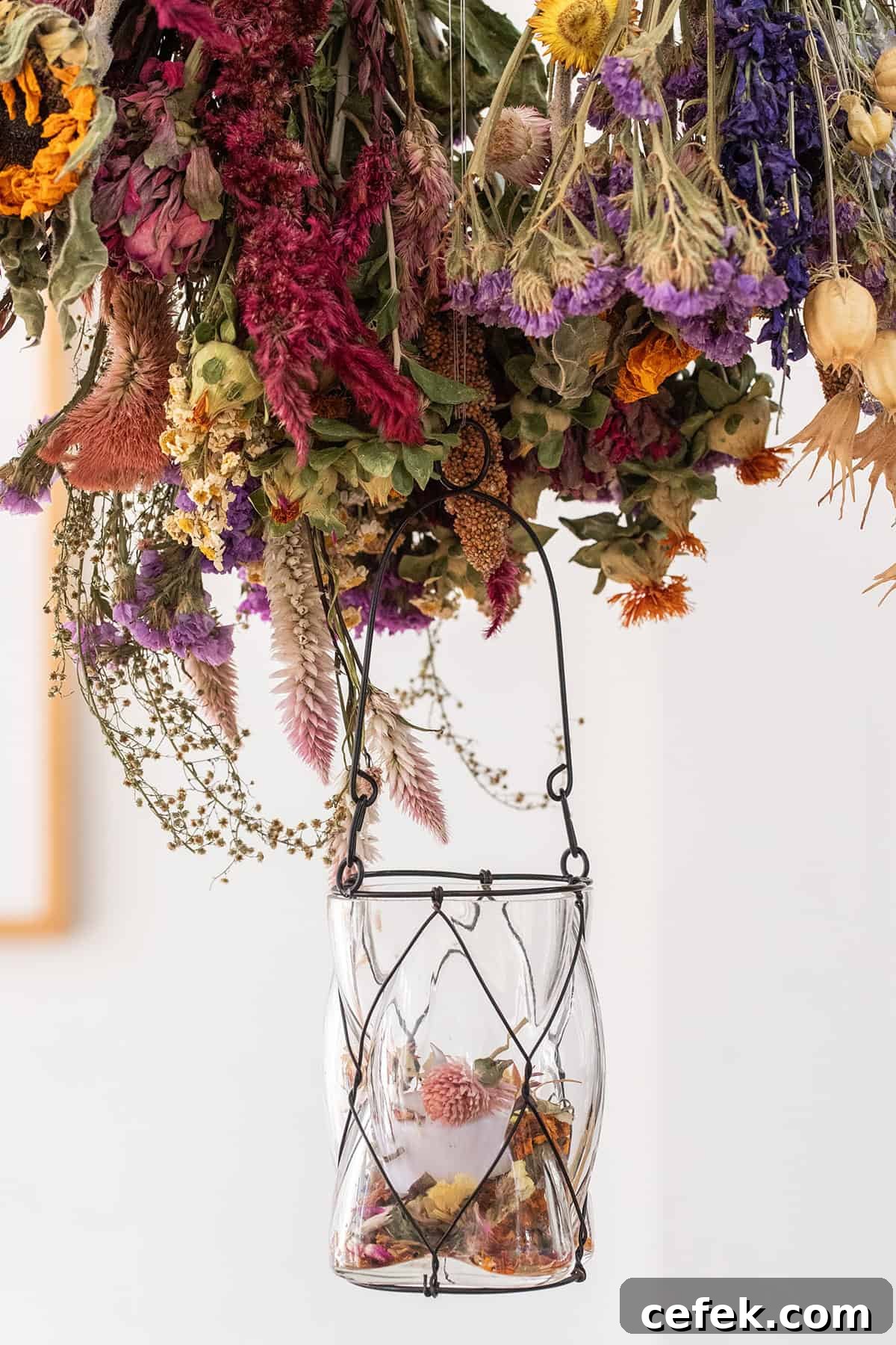 Lanterns hanging from a bar with dried flowers.