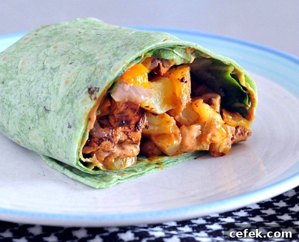 Chipotle Tofu Burrito wrapped in a green spinach tortilla, sliced in half and sitting on a plate 