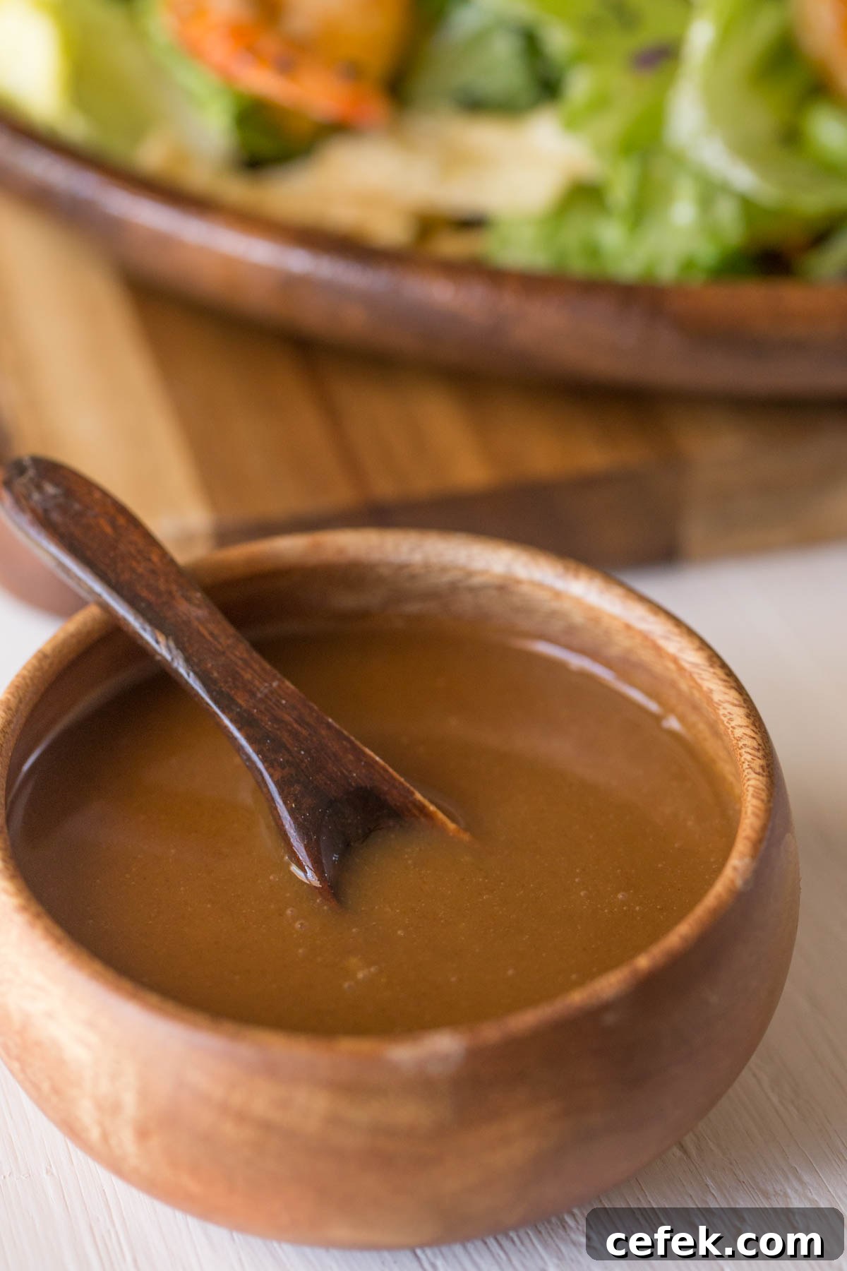 A small wood bowl of the Spicy Peanut Dressing with a little wooden spoon in it. 