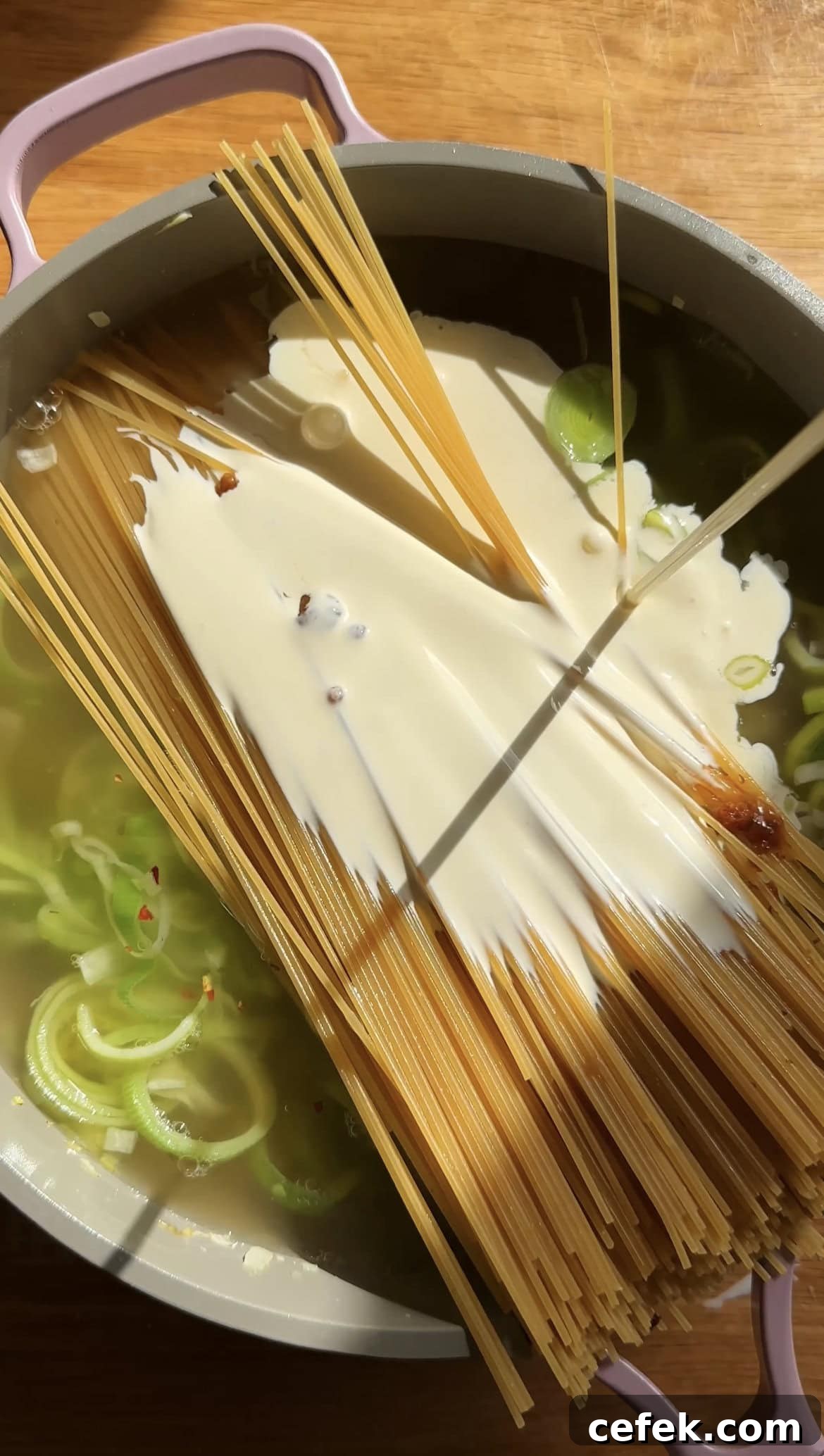 adding cream to pasta in a large saucepan