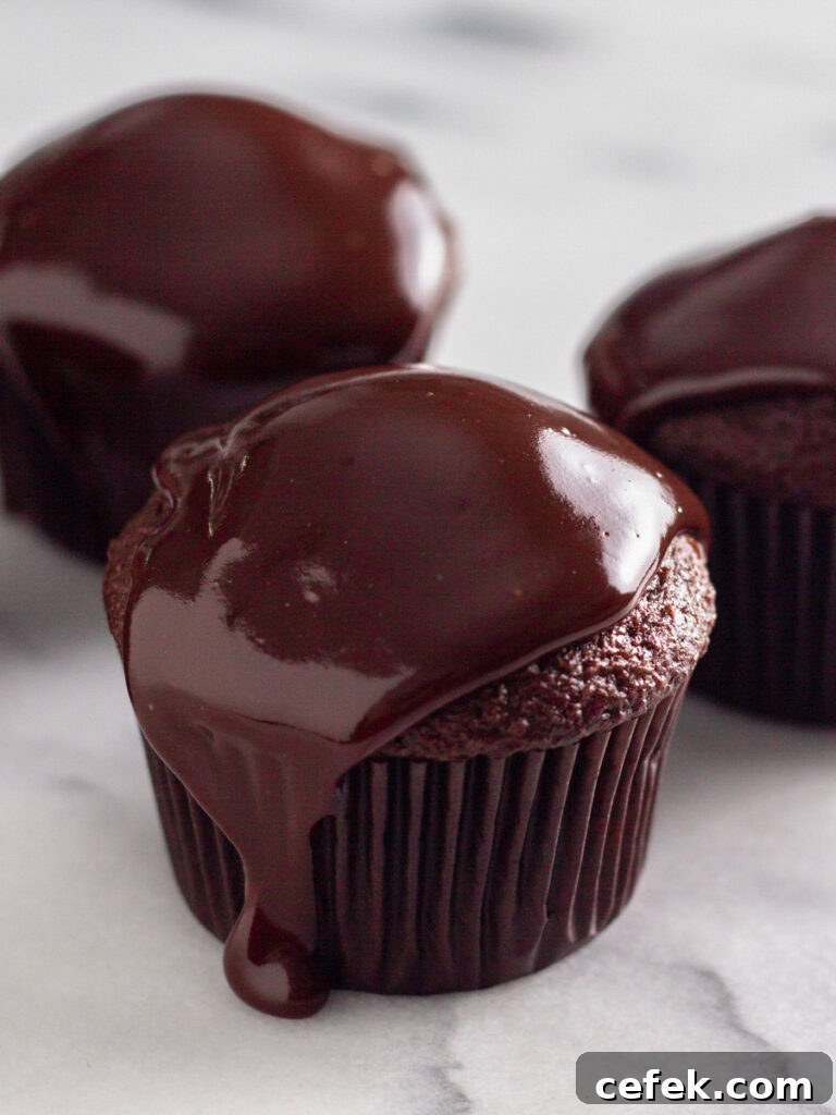 Perfect Chocolate Ganache Recipe for a Smooth, Glossy Finish 2 Three cupcakes with a chocolate ganache topping.