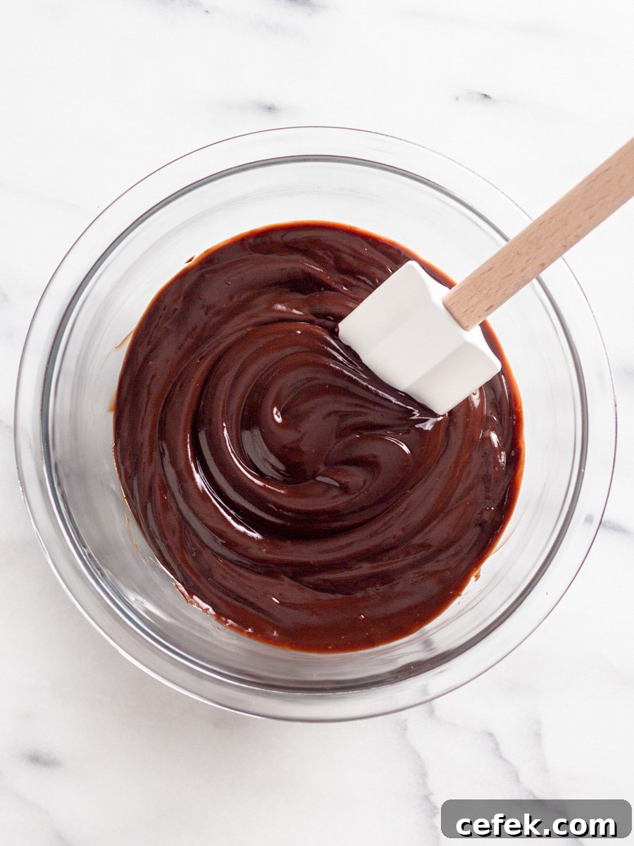 Perfect Chocolate Ganache Recipe for a Smooth, Glossy Finish 6 Mixing chocolate ganache in a bowl with a spatula.