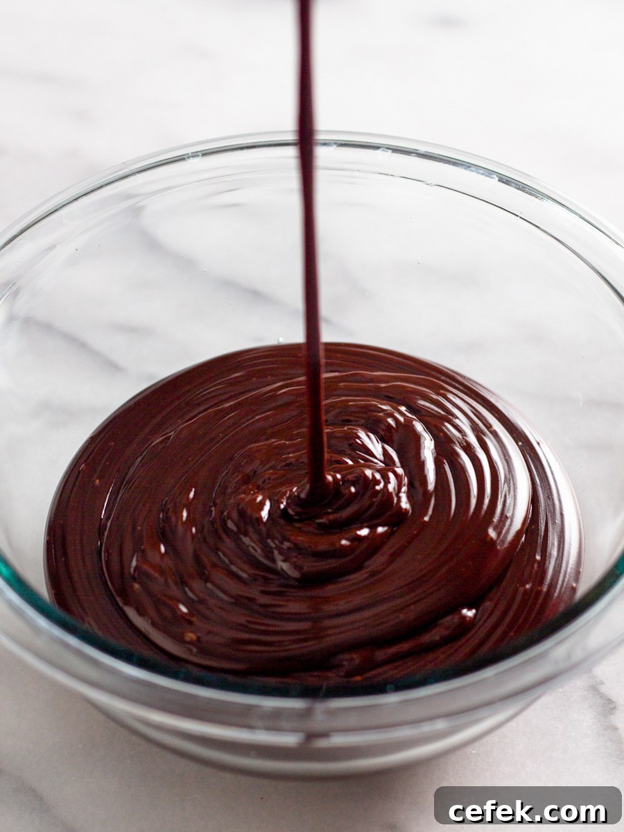 Perfect Chocolate Ganache Recipe for a Smooth, Glossy Finish 7 Chocolate ganache being drizzled into a bowl.