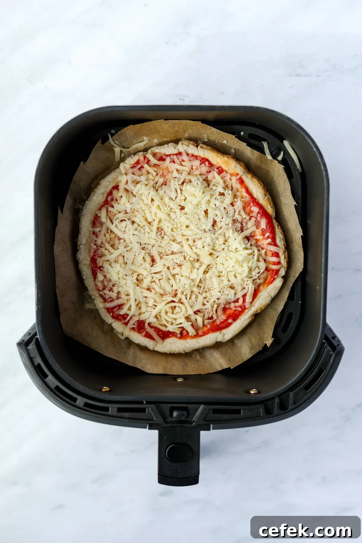 Greek Yogurt Pizza Recipe with Crispy Thin Crust 8 An air fryer with an uncooked mini pizza inside.