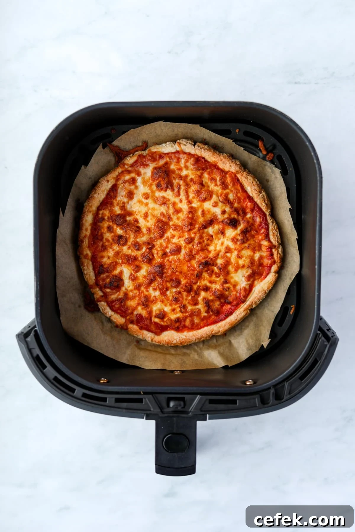Greek Yogurt Pizza Recipe with Crispy Thin Crust 9 An air fryer with a cooked cheese pizza inside.