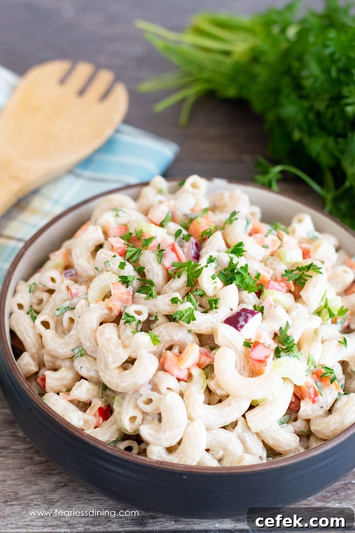Creamy Gluten-Free Macaroni Salad 8 A big bowl of deli style macaroni salad with a serving spoon and parsley.