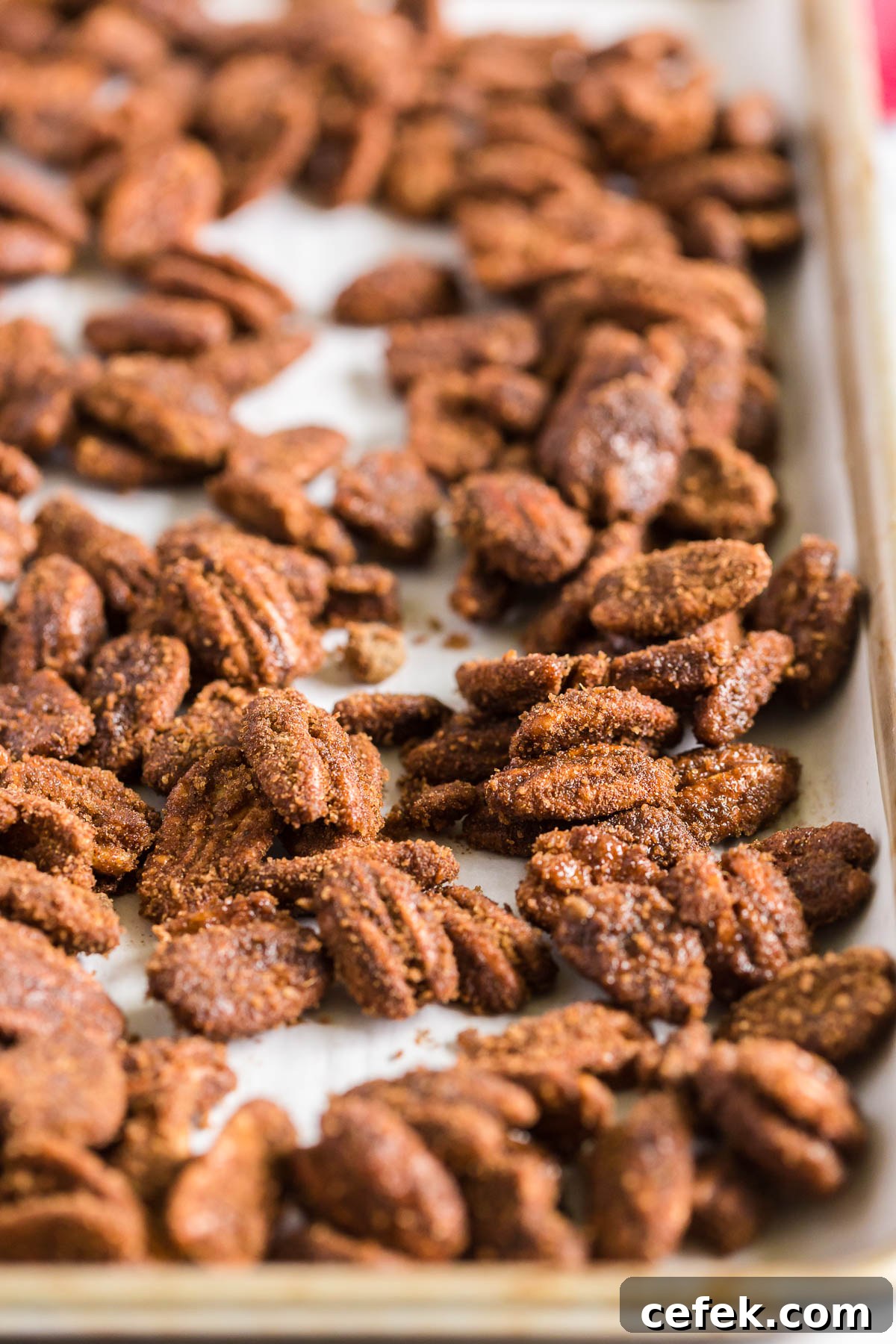 Gingerbread-Spiced Candied Pecans 8 Candied pecans scattered on a baking pan.