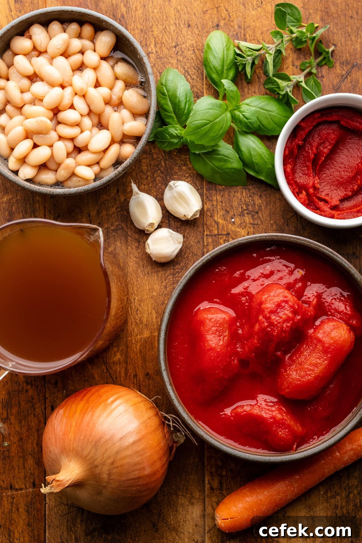 Ingredients for tomato basil soup arranged in different sized bowls on a wooden background.