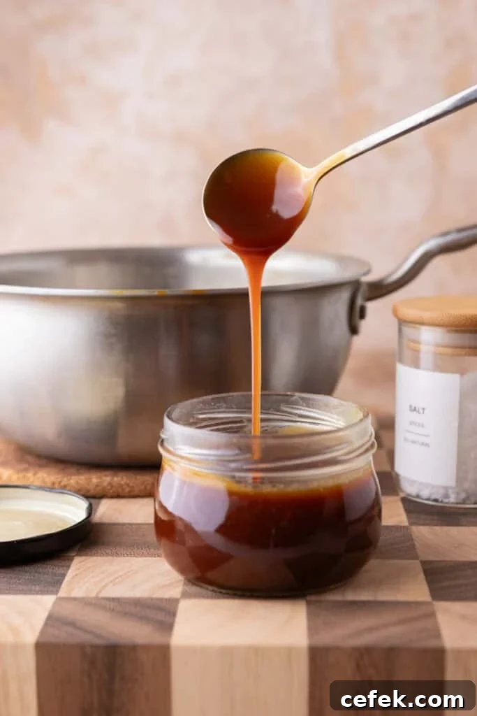 Spoon pouring homemade caramel sauce into jar