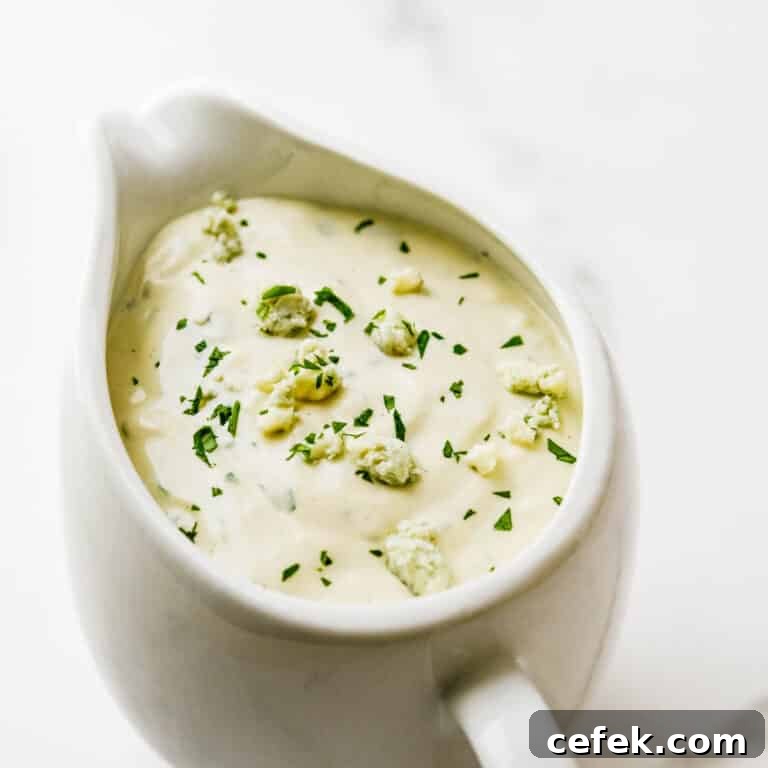 A pitcher of blue cheese dressing with cheese crumbled on top.
