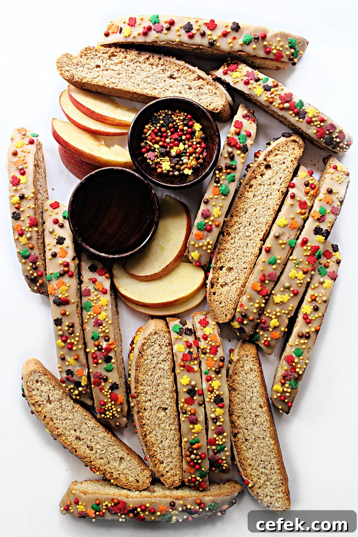 Apple Biscotti with cinnamon icing and fall leaf and pearl sprinkles on a white background.