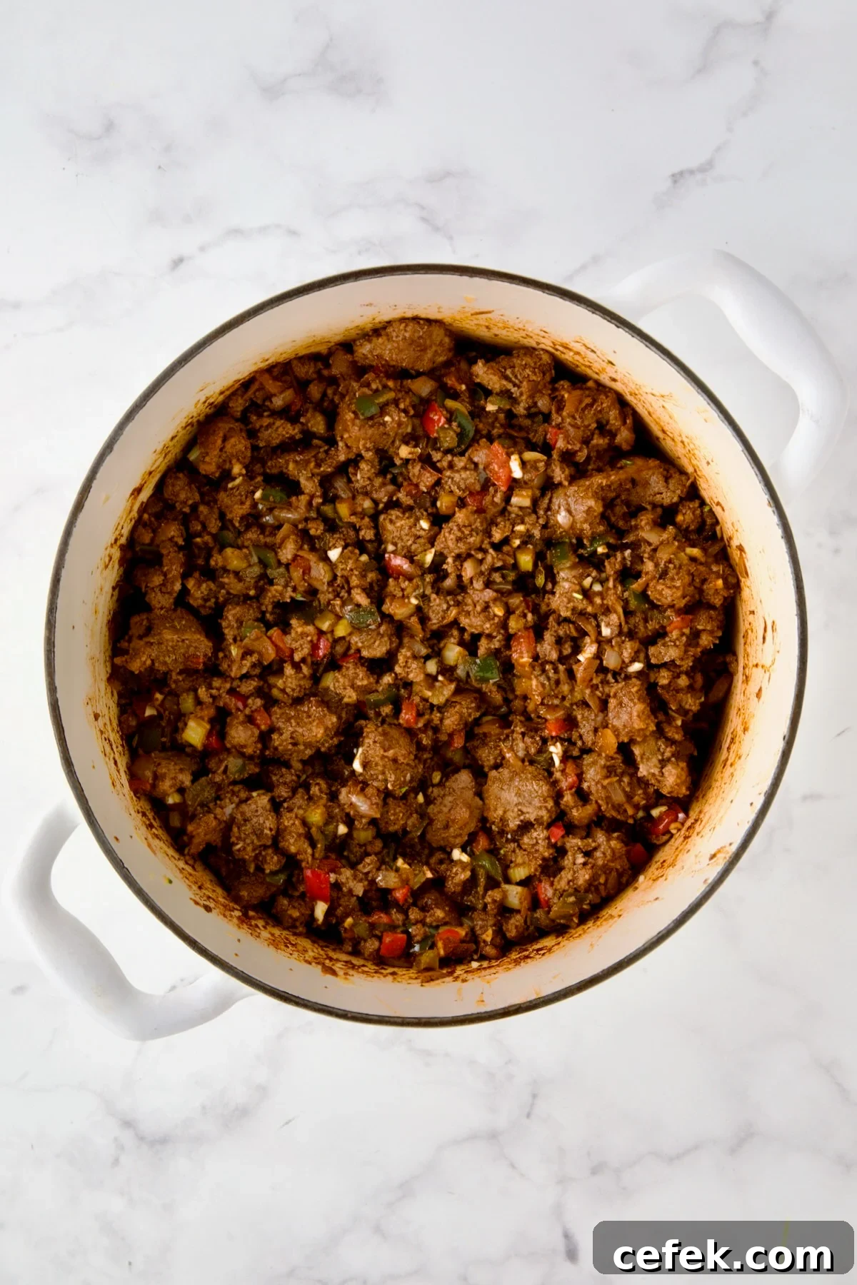 Beef and pork added back to white enamel Dutch oven with spices, vegetables and wine.
