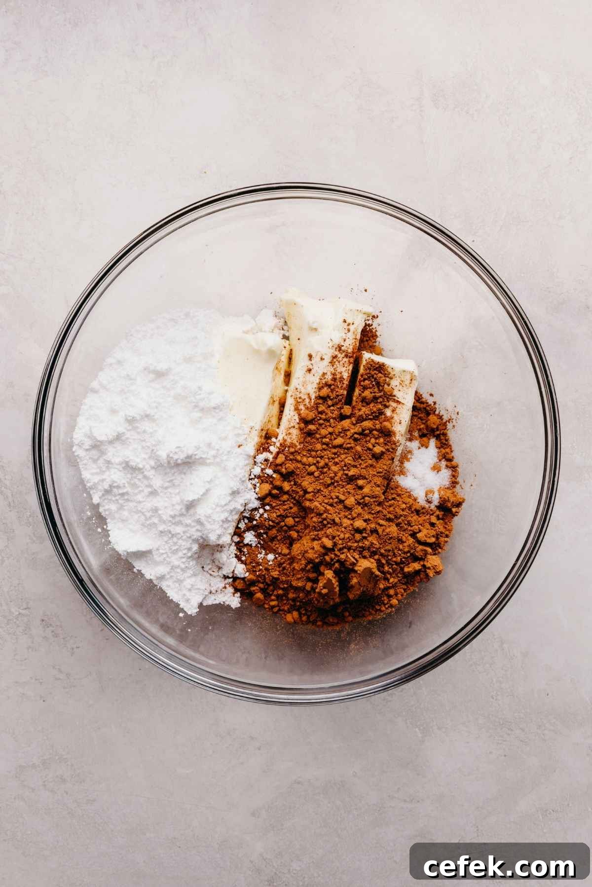 Classic Four-Egg Yellow Sheet Cake with Chocolate Frosting 13 Powdered sugar, unsweetened cocoa powder, butter, and salt added to a glass mixing bowl.